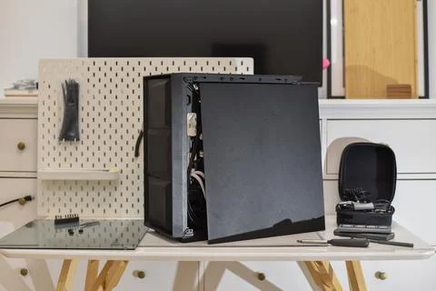 Black computer tower internal components, tools on white desk for assembly Foto stock