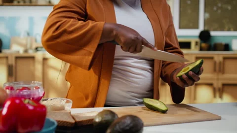 Black content creator cutting avocado in food video at the counter Stock Footage 333611249