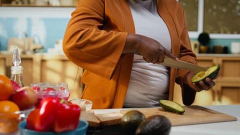 Black content creator cutting avocado in food video at the counter 写真素材