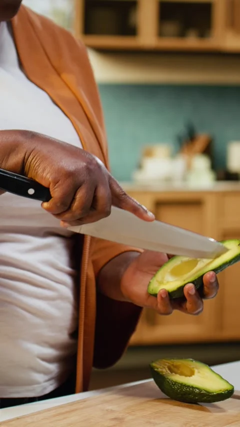 Black content creator, slicing avocado, cooking process, home chef Stock Footage 333616458