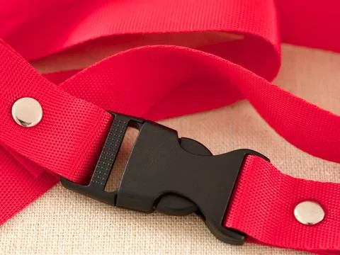 A black contoured side release plastic buckle with red nylon belt on a beige  Stock Photos