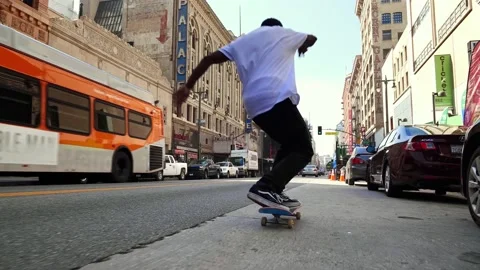 Black cool skateboarder jumping trick on street in Los Angeles. American hipster Stock Footage 131501034