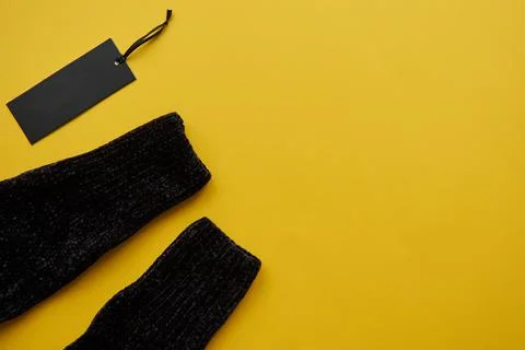Black cosy pullover and paper label isolated on yellow paper background. Clot Stock Photos
