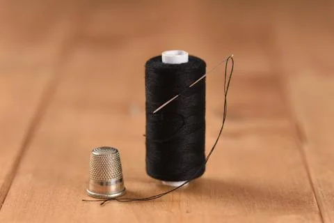 Black cotton thread bobbin with needle close up Stock Photos