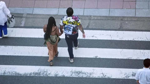 Black couple cross a intersection viewed from above. A pair of black pedestrians Stock Footage 308879244