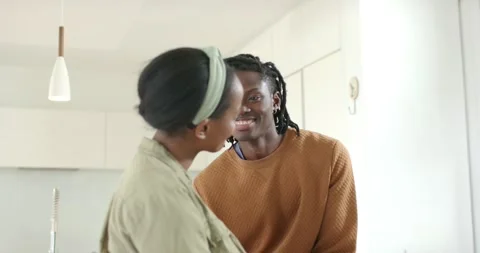 Black couple entering kitchen, exchanging greeting, hugging beside white Vídeo Stock 317964684