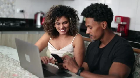 Black couple in front of laptop computer at kitchen table multi-tasking Stock Footage 156596390