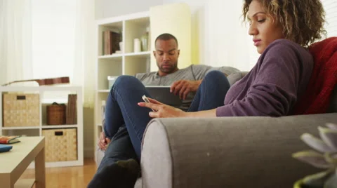 Black couple using electronic devices on sofa Stock Footage 41482175