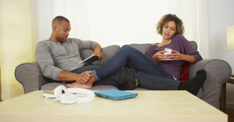 Black couple using electronic devices on couch Stock Footage 44498111