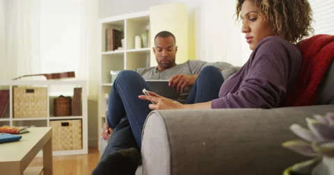 Black couple using electronic devices on sofa Video stock 44498155