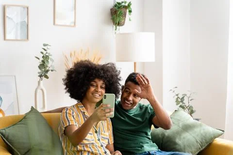 Black couple using smartphone on sofa Stock Photos