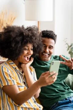 Black couple using smartphone on sofa Stock Photos