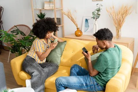 Black couple using smartphone on sofa Stock Photos