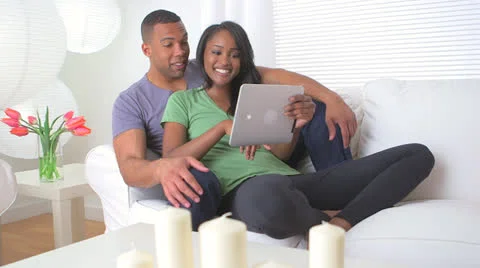 Black couple using tablet on couch Stock Footage 23879810