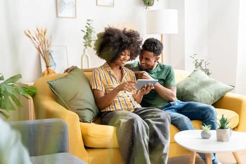 Black couple using tablet on sofa Stock Photos