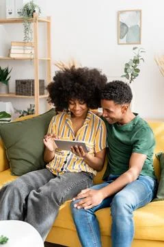 Black couple using tablet on sofa Stock Photos