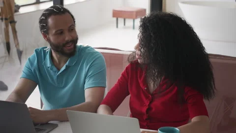 Black couple working on laptops and discussing tasks, small business owners Stock Footage 333781896