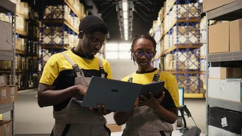 Black coworkers preparing orders in boxes for shipment in large warehouse Stock Photos