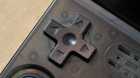 Black cross-shaped D-pad on a translucent retro handheld game controller, e.. Stock Footage 339372881