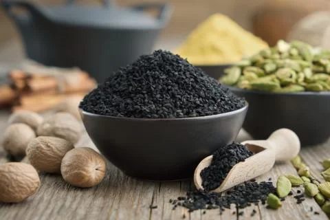 Black cumin or roman coriander seeds and aromatic spices on table. Stock Photos