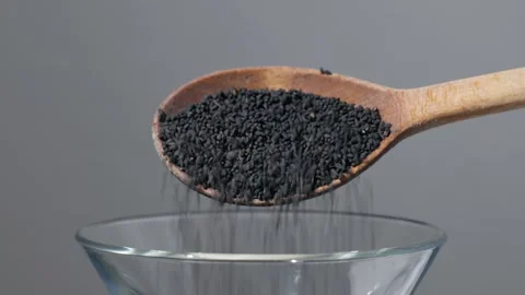 Black cumin seed falling from a wooden spoon Stock-Footage 343160145