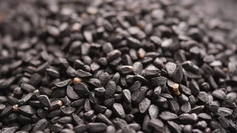 Black cumin seeds rotating on surface with extreme macro detail in slow mot.. Video stock 332882243