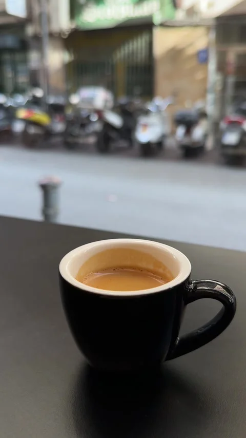 Black cup of espresso on cafe table with blurred urban background Stock Footage 294821345