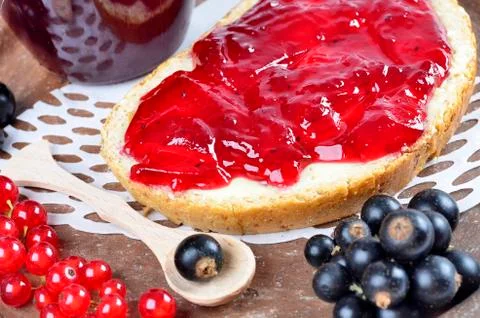 .Black currant jam on a slice and in a jar, close-up. Stock Photos