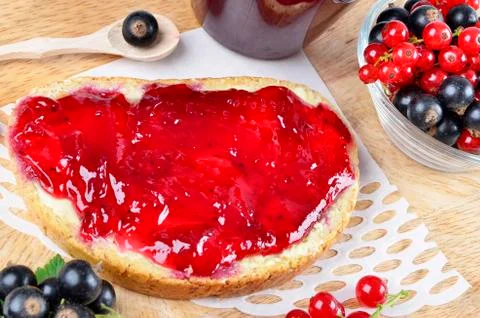 .Black currant jam on a slice and in a jar, close-up. Stock Photos
