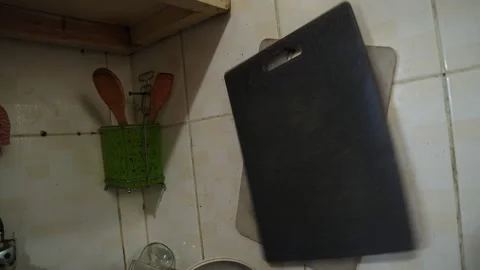 Black cutting board resting against kitchen tile wall Stock Footage 336763764