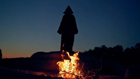 Black death behind the fire flame outdoors. Scary witch in black costume Stock-Footage 122681997