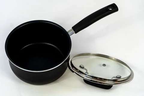 Black deep iron pan with a plastic handle and a glass lid on a white background Photos
