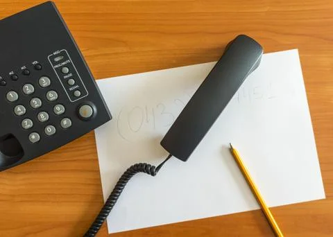 The black desktop push-button telephone on desk in office. Black phone with.. Stock Photos