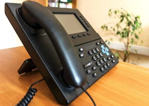 The black desktop push-button telephone. IP phone on desk in office. Stock Photos