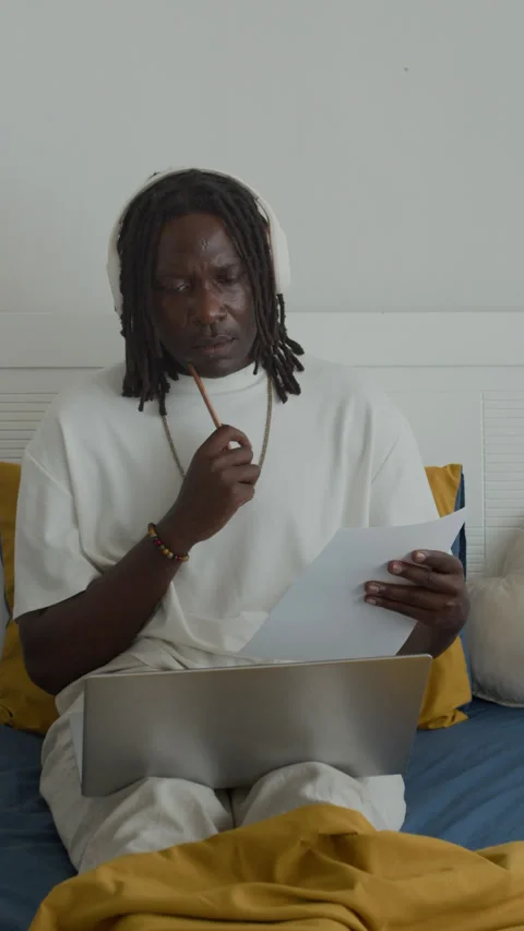 Black Developer in Headphones Using Laptop in Bed Stock Footage 300825229