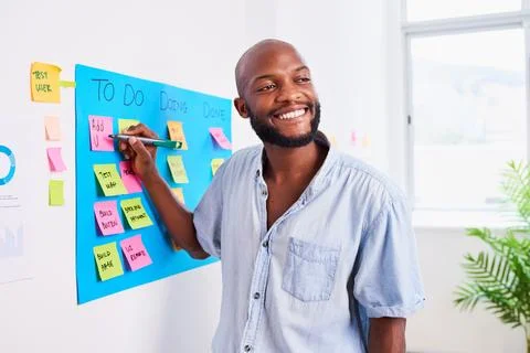 Black developer writes ticket on scrum board, sprint planning coding meeting 写真素材