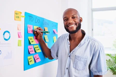 Black developer writes ticket on scrum board, sprint planning coding meeting Stock Photos