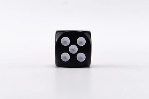 Black Dice with Five White Pips on a White Background, Close-up Studio Shot. Stock Photos