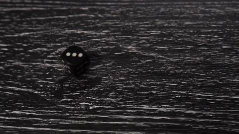 Black dice rolls and spins on a black wooden old table. Stops with the number Stock Footage 123119223