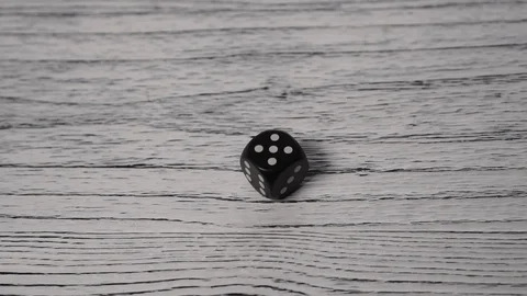 Black dice rolls on a white textured wooden old table. Stops with the number Stock Footage 123119256