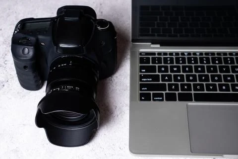 A black digital camera and a computer laptop on a table. Stock Photos