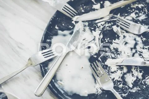 Black dish with fork knife and spoon empty after eat. Stock Photos