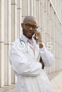 Black Doctor Talking On Cell Phone On City Street
