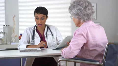 Black doctor talking to disabled elderly woman Видео 32425413