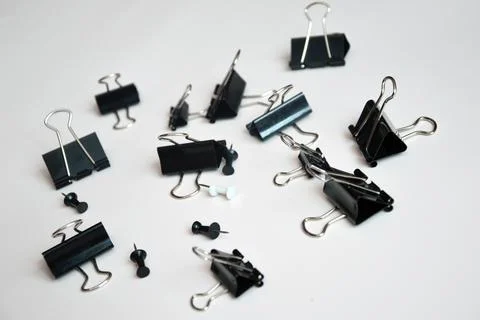 Black document clips and buttons scattered on a white background. Office tool Stock Photos