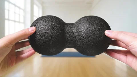 A black double peanut massage ball made of special foam displayed in a hand in a Video stock 280366135