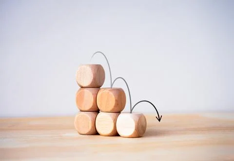 Black down arrows jumping down on wood blocks stacked, decrease business gr.. 스톡 사진