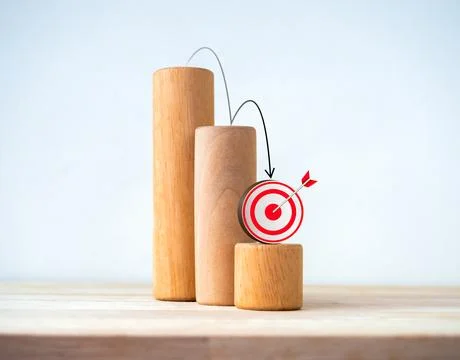Black down arrows jumping down on 3d target icon on wood blocks, decrease b.. Stock Photos