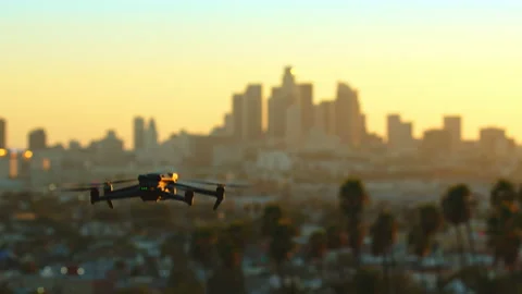 Black drone flies into the frame against center of the Los Angeles in the sunset Stock Footage 227860829