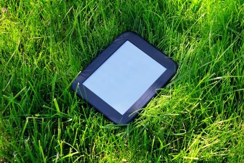 Black E-book lays on grass Fotos de archivo